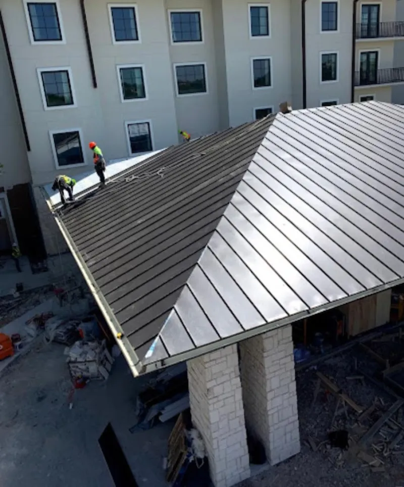 Crew installing standing seam metal roof panels on a commercial project in Hillsboro